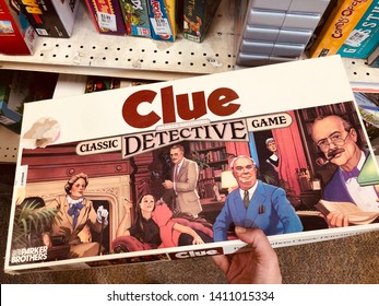 New Hope, Minnesota - May 26, 2019: Hand Holds A Classic, Vintage Clue Detective Board Game, From The 1990s. Made By Parker Brothers
