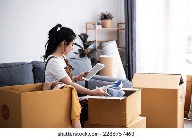 New house, asian woman check list of stuff in the box while feeling proud and excited about buying a house with a mortgage loan. Young asian woman first time buyers unpacking in dream home, apartment. - Powered by Shutterstock