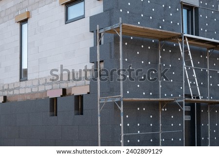 New House building in process insulation of the wall of the house with layers of modern thermal insulation materials . Exterior covering in construction site.