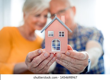 New House Concept, Happy Senior Couple Holding Small Home Model