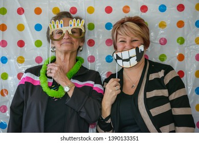 NEW IBERIA, L.A. / USA - FEBRUARY 28, 2015: Two Senior Citizen Women Pose For An Outdoor Photobooth Using Silly Props While Laughing And Having A Good Time.