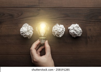 new idea concept with crumpled office paper, female hand holding light bulb - Shutterstock ID 258191285