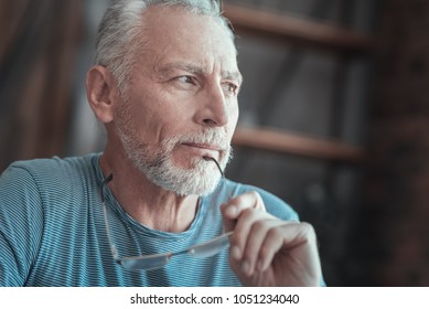 New Idea. Interested Deep Gray Haired Man Spending Time Alone Thinking And Holding The Glasses.