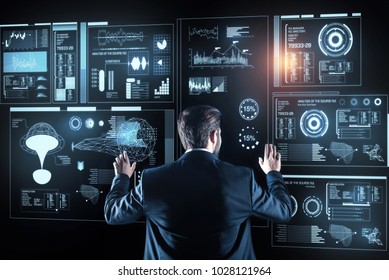 New information. Smart experienced programmer thoughtfully looking at the futuristic device while analyzing the information on it
