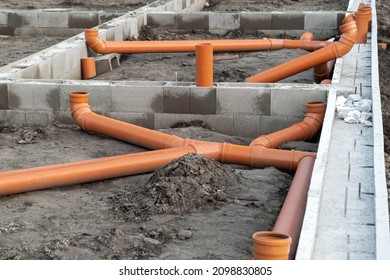New Installed pipework system. Sewer Line developed and mounted on the construction site. New Orange PVC plastic Drainage pipe Tube - Shutterstock ID 2098830805