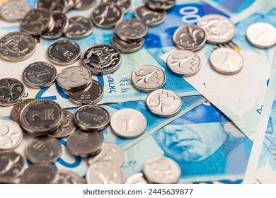 New Israeli shekel coins and bills lie on the table. Shekels.