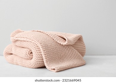 New knitted folded blanket on table near light wall - Powered by Shutterstock - Get 15% off with code: PIKWIZARD15