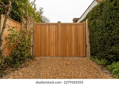 New large automatic wooden entrance gates at the end of a residential gravel driveway  
