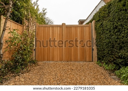 New large automatic wooden entrance gates at the end of a residential gravel driveway  