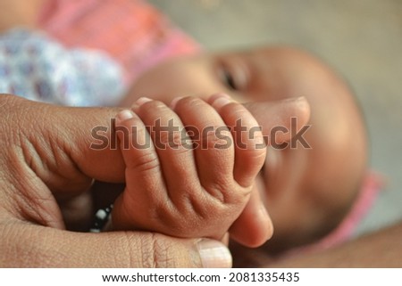 New little baby holding finger of her father mother