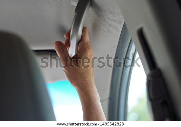 New London, CT / USA -\
June 22, 2019: Middle aged hands holding on to the grab handle in a\
casual car