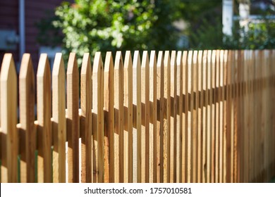 New Looking Fence Around A House In A Rural Area Of City, Raw Brown Wood With Pointy Tops To Protect And Secure Area Of Land Around House