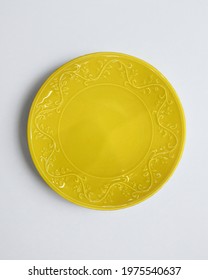 New luxury plate view from above on a isolated white background. Top view. Porcelain yellow saucer with a plant pattern. Trendy Coral tones. Flat lay view. Indian style.