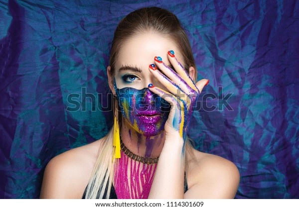 New make-up universe is painted on womans face.
Forehead brows eyes are chic evening make-up green color, wavy line
divides the face into two parts. At the bottom of her face are
streams vivid paint