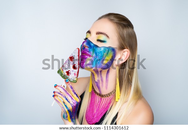 New make-up universe is painted on womans face.\
Forehead brows eyes are chic evening make-up green color, wavy line\
divides the face into two parts. At the bottom of her face are\
streams vivid paint