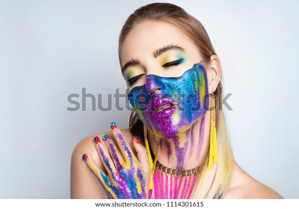 New make-up universe is painted on womans face.\
Forehead brows eyes are chic evening make-up green color, wavy line\
divides the face into two parts. At the bottom of her face are\
streams vivid paint