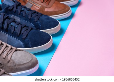 New male's multi-colored sneakers stacked in a row. Shoe tips close-up. Pink and blue background. Close-up. Copy space. The Shoemaker's Holiday concept.
