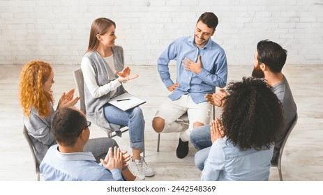 New member at rehab. Happy people clapping at support group meeting, welcoming cheerful guy, free space - Powered by Shutterstock