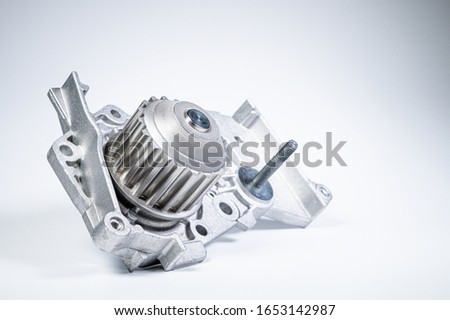 New metal automobile pump for cooling the engine of a water pump on a gray background. The concept of new spare parts for the car engine