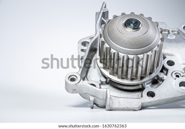 New metal automobile pump for cooling the engine\
of a water pump on a gray background. The concept of new spare\
parts for the car engine