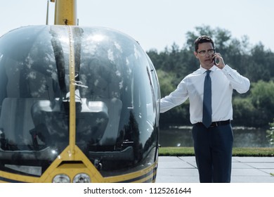 New Mission. Handsome Young Police Officer Talking On The Phone And Opening A Helicopter Door While Being Ready To Be Off To A New Mission