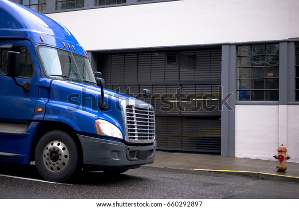 New modern blue large class 8 semi truck with
trailer for long haul and local transportation and delivery of
cargo and goods from warehouses to retail outlets and businesses on
city street