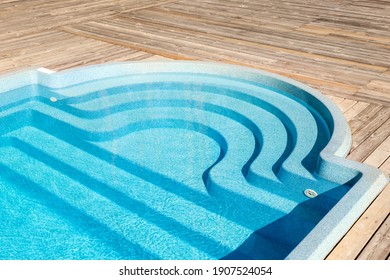 New Modern Fiberglass Plastic Swimming Pool Entrance Step With Clean Fresh Refreshing Blue Water On Bright Hot Summer Day At Yard Or Resort Hotel Spa Area. Wooden Flooring Deck Of Teak Or Larch Board