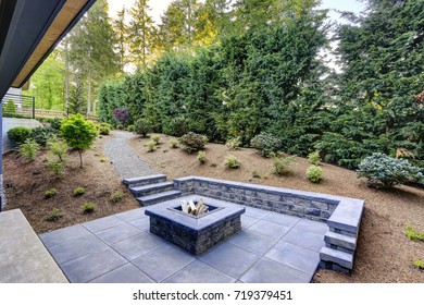 New modern home features a backyard with rectangular concrete fire pit framed by slate pavers and overlooking the lush garden. Northwest, USA
