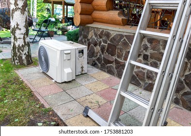 New Modern HVAC Air Conditioning External Compressor Unit Preapred For Installation Or Replacement Near Wall Of Wooden Log Residential Country Cottage. Ladder And Equipment For Service And Maintenance