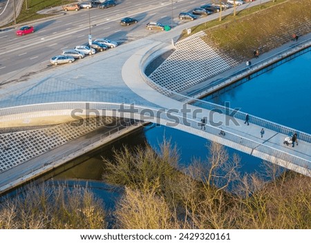 New modern pedestrian bridge over the river. Aerial photo of rounded shapes bridge in Kaunas, Lithuania