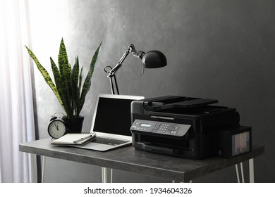 New modern printer and laptop on grey table in office