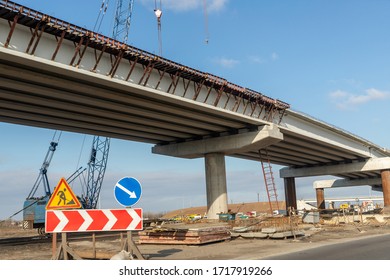 New Modern Road Highway Bridge Overpass Contruction Site Overhead View With Heavy Industrial Machinery And Blue Sky On Background. Urban City Infrastructure Development