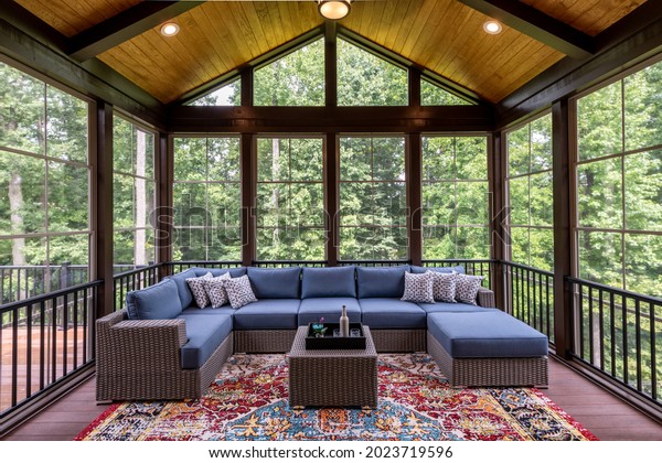 New modern screened porch with patio\
furniture, summertime woods in the\
background.