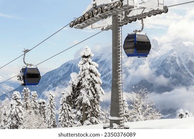 New modern spacious big cabin ski lift gondola against snowcapped forest tree and mountain peaks covered in snow landscape in luxury winter alpine resort. Winter leisure sports, recreation and travel