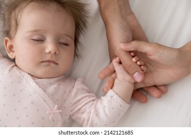 New Mom And Dad Holding Hand Of Beautiful Sleepy Baby Girl. Few Month Kid Resting On Bed With Couple Of Parents. Close Up Of Hands, Cropped Shot. Childcare, Parenthood, Family Concept