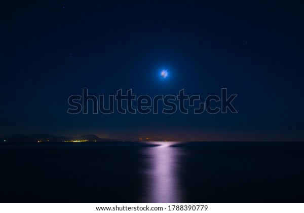 New
moon in the starry sky and lunar path on the sea against the island
lights. Milky way. Astronomy and cosmology
science.