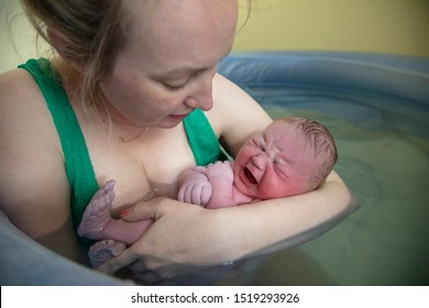 A new mother embracing her newborn baby after a natural pool home birth