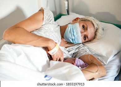 A New Mother Nursing Her Newborn Little Boy In Facial Mask During Pandemic