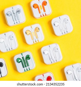 New Multicolor Earphones In Plastic Storage Cases On Yellow Background