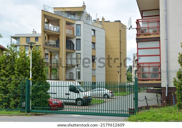 New multi-family buildings with cars\
parked in the parking lot are fenced with a\
fence