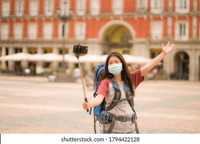 New Normal Backpacker Girl Travel In Europe - Young Happy And Beautiful Asian Chinese Tourist Woman In Face Mask Taking Selfie With Mobile Phone And Stick Enjoying City And Urban Sightseeing