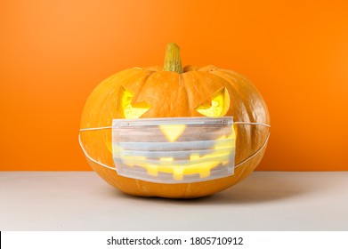 New normal concept. Glowing Halloween pumpkin in a protective medical mask on a orange background. Copy space. - Powered by Shutterstock