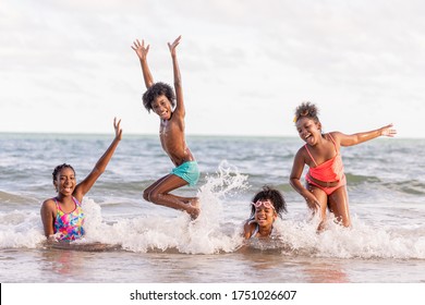 New Normal Concept.african American,group Of Children Or Brothers And Sisters Jump Into The Sea Happy While Traveling With Family Or School During Summer Or Vacation After Unlocking Down From COVID19