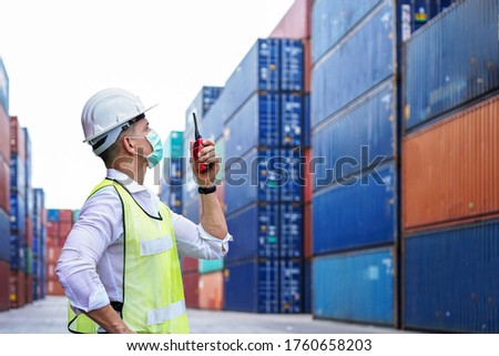 new normal concept.inspector engineer or project engineer wear helmet and mask and use walkie talkie to contact the factory team or container yard.Remote execution to prevent Coronavirus infection