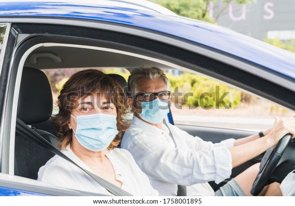 New normal. Driver with a medical face mask\
driving a car with a passenger. Health protection. Family in the\
car protected by a mask safety and pandemic concept. Coronavirus\
devices. Social distance.