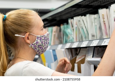 New Normal Retail Shopping. Teenage Blond Girl Wearing Face Mask Choosing Stationery In The Retail Shop. School Supplies. Back To School Shopping