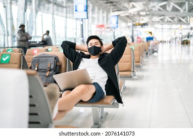 New normal and social distance concept.Asian young man tourist wearing mask using laptop searching airline flight status and sitting with distance during corona virus 2019 outbreak at airport - Powered by Shutterstock