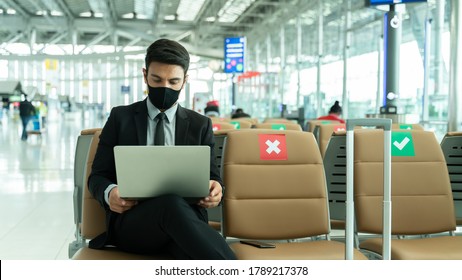 New normal and social distance concept.Business man wearing mask using smartphone searching airline flight status and sitting with distance during corona virus 2019 outbreak at airport - Powered by Shutterstock