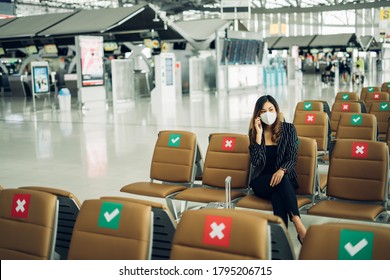 New normal and social distance concept.businesswoman wearing face mask using smartphone searching airline flight status and sitting with distance during coronavirus2019 outbreak at airport - Powered by Shutterstock