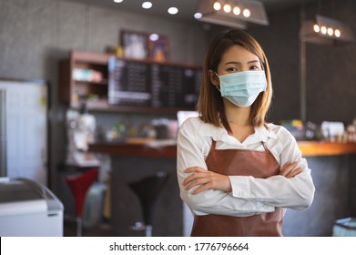 New normal startup small business Portrait of Asian woman barista wearing protection mask stand in her coffee shop while social distancing